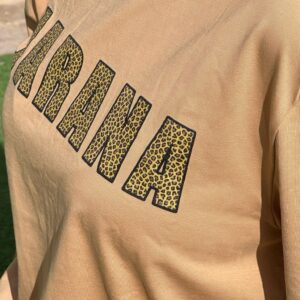 Camiseta JARANA Safari Chill de algodón orgánico, con estampado leopardo sobre fondo color arena y letras rellenas estilo street.